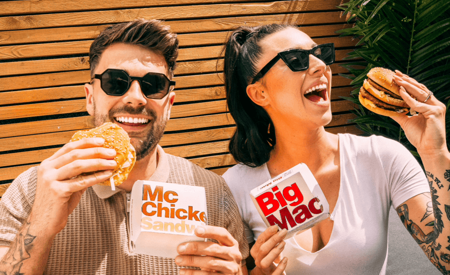 A man and a woman holding McDonal's burgers and smiling